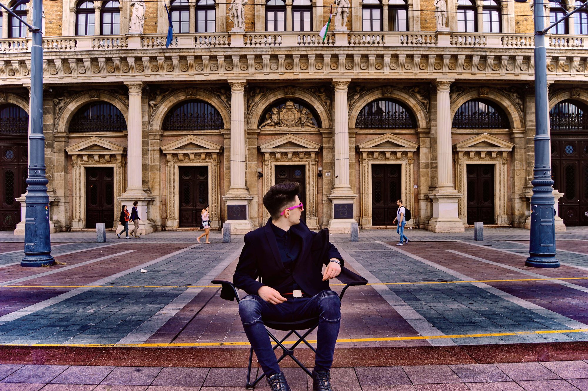 Károly Bödei seated in a plaza before a grand Budapest building